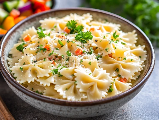 A bowl of bowtie pasta topped with parsley and mixed vegetables, highlighting its versatility in both creamy and light dishes.