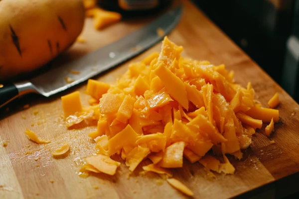 Freshly chopped sweet potatoes on a wooden cutting board with a knife