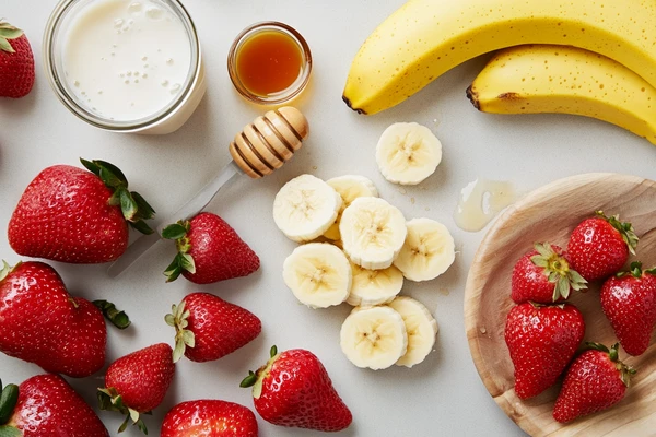 Ingredients for Strawberry and Banana Smoothie without yogurt, including strawberries, bananas, honey, and milk.