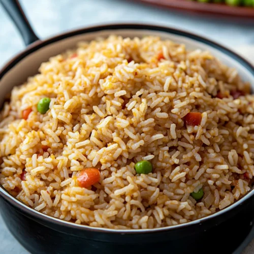 A close-up of a bowl filled with flavorful Cajun rice, garnished with green peas and diced tomatoes.