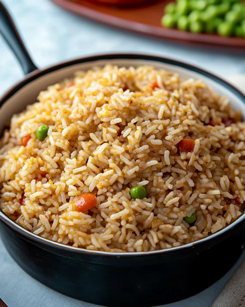 A close-up of a bowl filled with flavorful Cajun rice, garnished with green peas and diced tomatoes.
